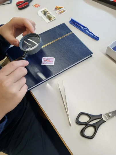 Kind schaut sich Briefmarke unter der Lupe an